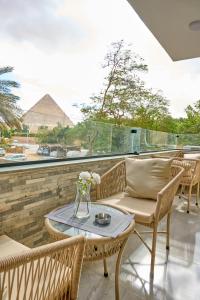 a patio with chairs and a table with a pyramid in the background at Lotus Inn in Cairo