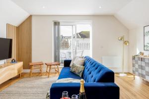 a living room with a blue couch and a tv at Sea Breeze - Coast in Bournemouth