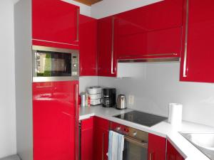 uma cozinha vermelha com balcões brancos e armários vermelhos em Gite de la Rhosnes em Amougies