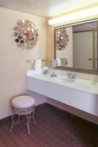 baño con lavabo, espejo y taburete en MCM Elegante Hotel & Suites Lubbock, en Lubbock