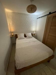 a small bedroom with a bed with white sheets at Tropic Valley Lodge in Vieux-Habitants