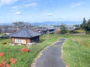 a small house in a field next to a road at ゲストハウスでたらめ荘 in Yamakami