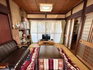 a living room with a leather couch and a tv at Guest House DETARAMESO in Yamakami