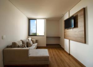 een woonkamer met een bank en een flatscreen-tv bij Ilhéus Praia Hotel in Ilhéus