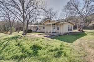 a small yellow house in a field with trees at Charming Austin Home on 2 Acres 11 Mi to Dtwn! in Bee Cave