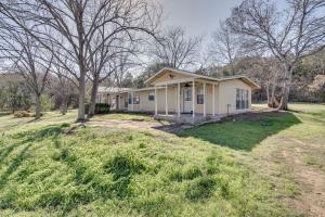 a small yellow house in a field with trees at Charming Austin Home on 2 Acres BBQ and Yard! in Bee Cave
