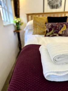 a bed with two towels on top of it at Hideaway Cottage in Ludlow