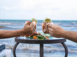 two people holding up jars of food on a table at the beach at Nirvana Resort in Lívingston