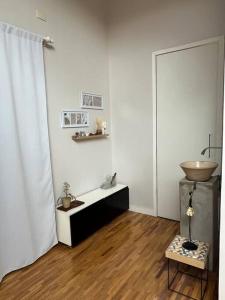 um quarto com paredes brancas e piso em madeira com uma mesa em Loft em Guaratinguetá - SP em Guaratinguetá