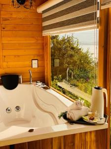 a bathroom with a bath tub and a window at Glamping Domos del Lago in Aquitania