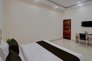 Schlafzimmer mit einem Bett, einem Schreibtisch und einem TV in der Unterkunft OYO Hotel Sunrise in Noida