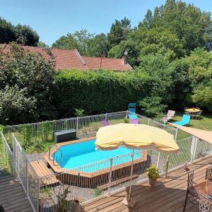 una piscina con sombrilla y sillas en Le Relais du Fraysse - Chambres d'hôtes, en Le Fraysse
