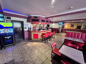 a restaurant with a bar with red chairs and a video game at Brig Inn Hotel in Aberdeen