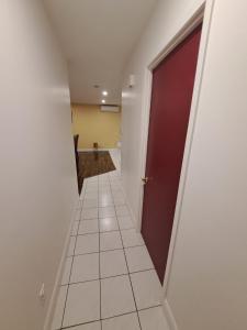 korytarz z czerwonymi drzwiami i podłogą wyłożoną kafelkami w obiekcie Auberge Motel LA RÉFÉRENCE w mieście Trois-Rivières