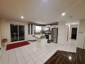 a large kitchen with white tile floors and a red rug at Auberge Motel LA RÉFÉRENCE in Trois-Rivières