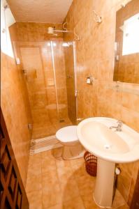 a bathroom with a sink and a toilet and a shower at Chalés Aldeia dos Lençóis in Santa Cruz Cabrália