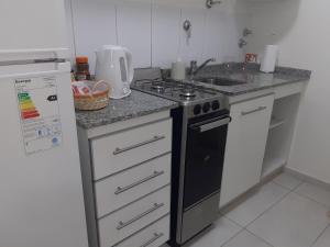 a kitchen with a stove and a white refrigerator at Departamento El Olivo con cochera in Santa Rosa
