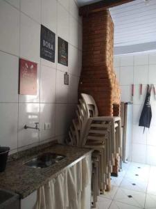 a kitchen with a sink and a row of chairs at Balneário Jussara in Mongaguá