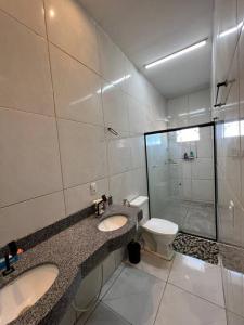 Un baño con dos lavabos, un inodoro y una ducha. en Darocha Salinas, en Salinópolis