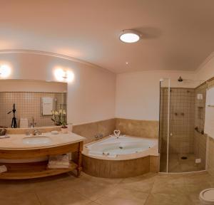 y baño con bañera, 2 lavabos y ducha. en Hotel Solar d'Izabel, en Campos do Jordão