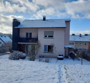 una casa blanca con nieve en el suelo en Ferienwohnung Haus Waldblick en Daun