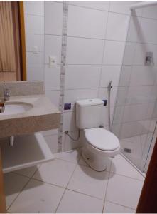 a white bathroom with a toilet and a sink at Condominio Barretos Thermas Park apto 312 in Barretos
