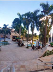 a courtyard with tables and palm trees and a pool at Condominio Barretos Thermas Park apto 312 in Barretos