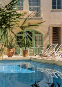 a swimming pool with chairs and a building at Mythos Suites Boutique Hotel in Rethymno Town