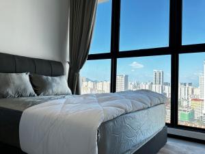 Bett in einem Zimmer mit einem großen Fenster in der Unterkunft Urban Pleasure Suites Central of GeorgeTown Jelutong in Jelutong