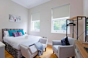 1 dormitorio con 1 cama, 1 silla y ventanas en Bright and cheerful studio, en Londres