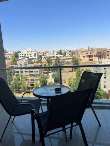 a table and chairs on a balcony with a view of a city at Luxury 2-bedroom Apartment Abdoun tower in Amman