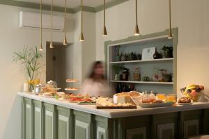 a woman is standing behind a buffet of food at Mythos Suites Boutique Hotel in Rethymno