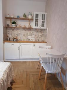 a kitchen with white cabinets and a table and chairs at Lawendowy Raj in Pilchowice