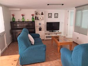 ein Wohnzimmer mit 2 blauen Stühlen und einem TV in der Unterkunft Alojamiento Casa Piano in Mairena del Aljarafe