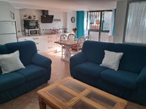 ein Wohnzimmer mit zwei blauen Sofas und einem Tisch in der Unterkunft Alojamiento Casa Piano in Mairena del Aljarafe