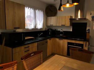 - une cuisine avec des placards en bois, une table et un évier dans l'établissement L’aureilhannaise, à Aureilhan 5 autres photos