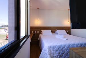 a bedroom with a bed with white sheets and a window at Ilhéus Praia Hotel in Ilhéus