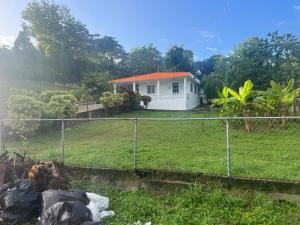 a house with a fence in front of a yard at Coqui del corazón Guest House in Hatillo