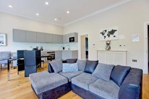 sala de estar con sofá azul y cocina en Stunning 1bed Kensington en Londres