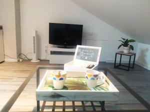 uma sala de estar com uma mesa de centro e uma televisão em Suite Mansardée indépendante, 25min Lyon-Villefranche em Chazay-dʼAzergues