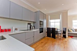 a kitchen with white cabinets and a table with chairs at Large 2bed Kensington in London