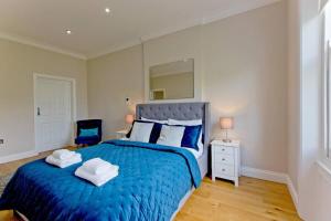 a bedroom with a blue bed with two towels on it at Large 2bed Kensington in London