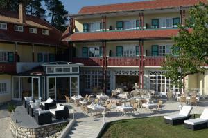 a hotel with tables and chairs in front of a building at Lust und Laune Hotel am Wörthersee in Pörtschach am Wörthersee