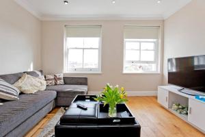 a living room with a couch and a tv at Super 2bed Kensington in London