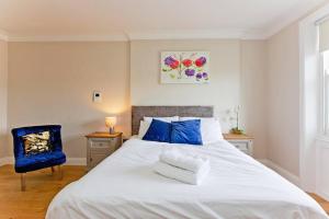 a white bed with blue pillows and a blue chair at Super 2bed Kensington in London