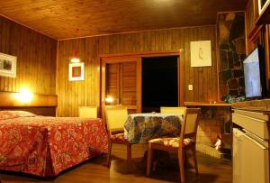 - une chambre avec un lit, une table et des chaises dans l'établissement Chalets do Vale, à Gramado