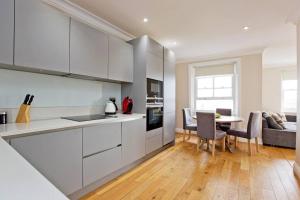 una cucina con armadi bianchi, tavolo e divano di Super 2bed Kensington a Londra