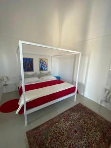 a white bed with a red and white canopy in a bedroom at Tenuta Miro in Ostuni