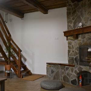 a living room with a stone fireplace and stairs at Bogáncs Vendégház - Nagybörzsöny in Nagybörzsöny