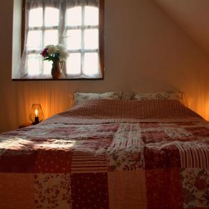 a bed with a red and white quilt in a bedroom at Bogáncs Vendégház - Nagybörzsöny in Nagybörzsöny